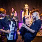 Boys playing keytars and girl singing in background