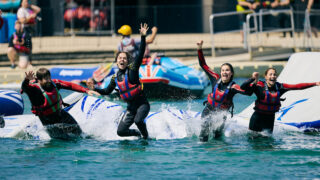 people jumping off the obstacle course into the water