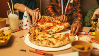 a pizza on a plate and a birthday hat