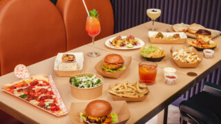 a table with burgers, pizza and nachos