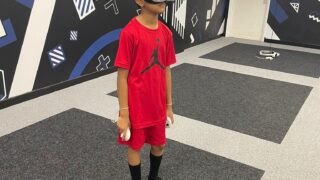 boy wearing red stood in VRXtra Kingston with a VR mask on and holding controllers.