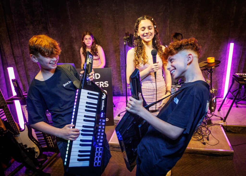 Boys playing keytars and girl singing in background