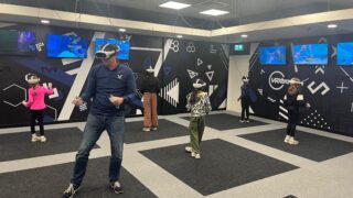 a man and lots of kids all playing a multiplayer VR game, wearing VR headsets at VRXtra Kingston