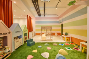 Image of play area with striped walls, fake grass and play equipment