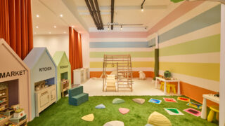 Image of play area with striped walls, fake grass and play equipment
