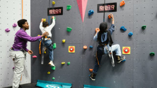 Kids on Climbing wall being helped by adult at WEST Youth Zone