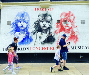 family walking past a Les Mis poster